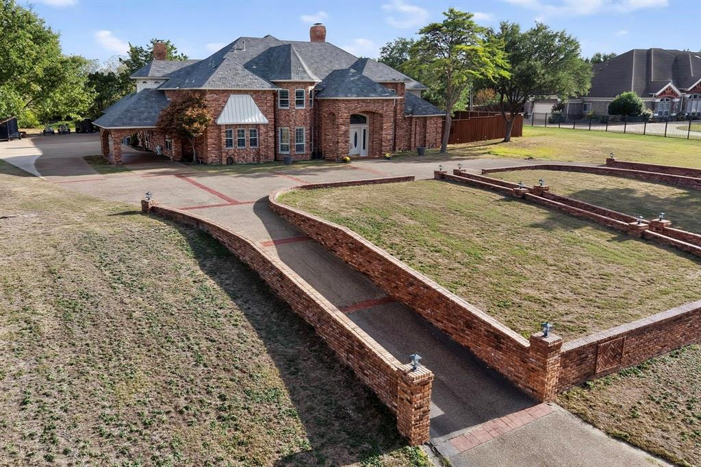 Multi-story brick exterior featuring a prominent turret, arched entryway, double front doors with leaded glass accents, and a custom-patterned concrete driveway