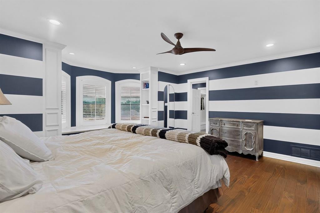 Room featuring wood-finish flooring, recessed lighting, a modern ceiling fan, built-in shelving, and bay windows with plantation shutters
