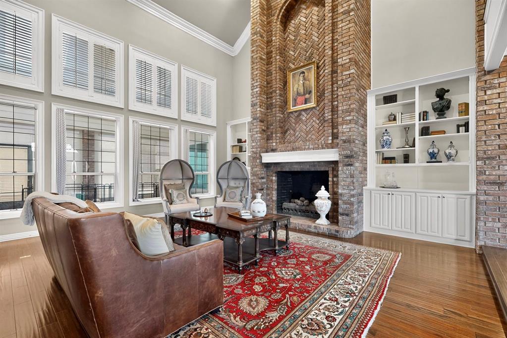 Vaulted ceilings, floor-to-ceiling brick fireplace with a herringbone pattern, integrated white built-in cabinetry, grid-patterned multi-pane windows, and wood-finish flooring