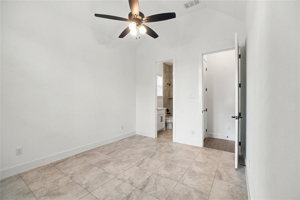 Vaulted ceiling, ceiling fan with integrated lighting, tiled flooring, white walls, and a white door with black hardware