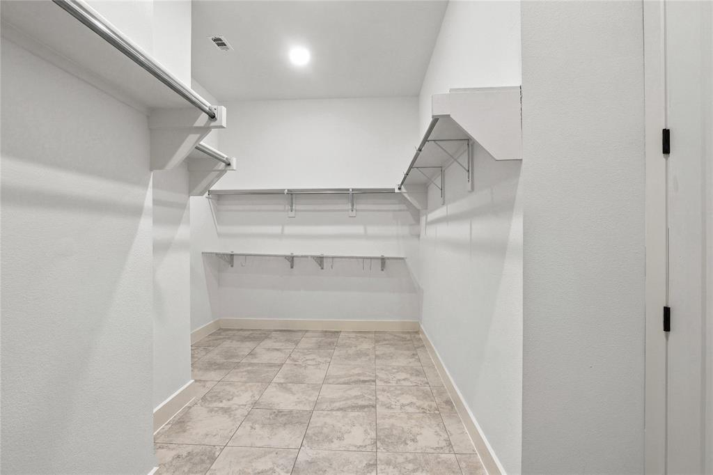 Walk-in closet featuring built-in shelving, hanging rods, recessed lighting, and tile flooring