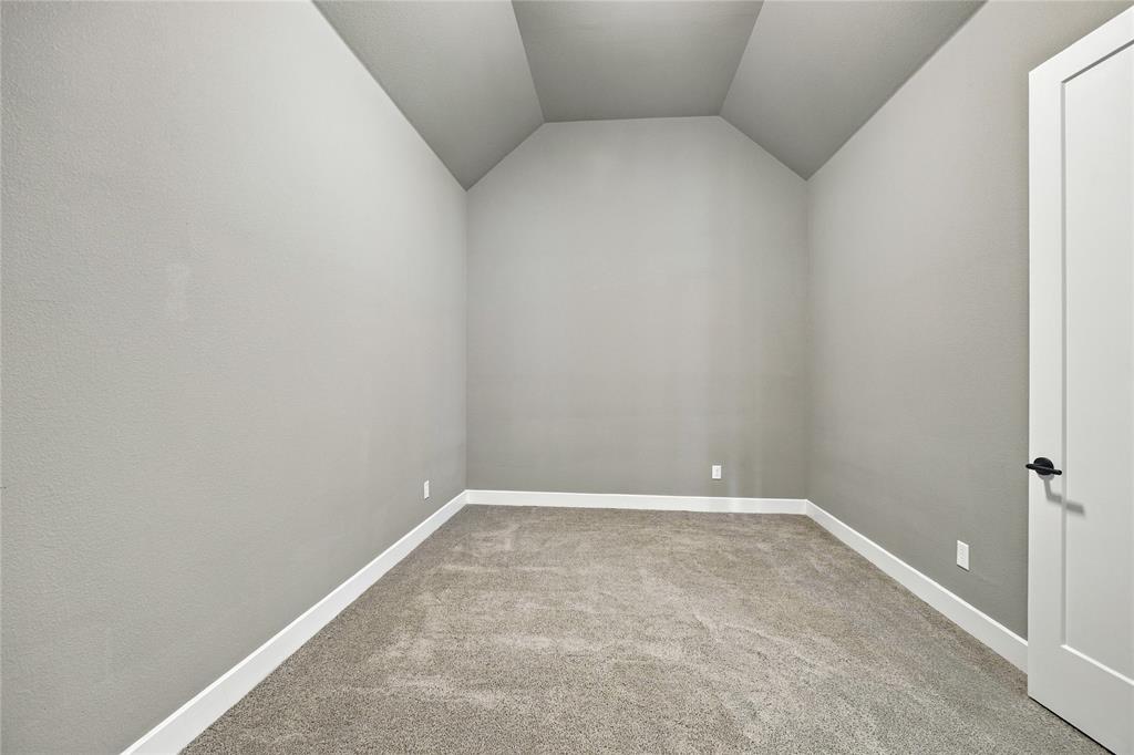 Vaulted ceiling, neutral wall paint, carpet flooring, white trim, and a contemporary door with matte black hardware