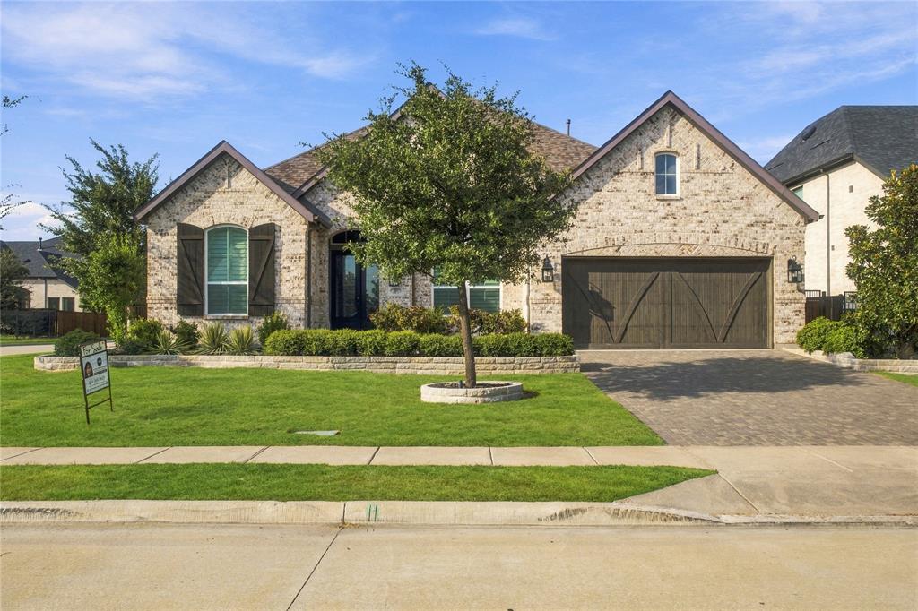 Brick elevation with dark wood-finish garage door, arched entry, and shuttered windows Brick elevation with dark wood-finish garage door, arched entry, and shuttered windows