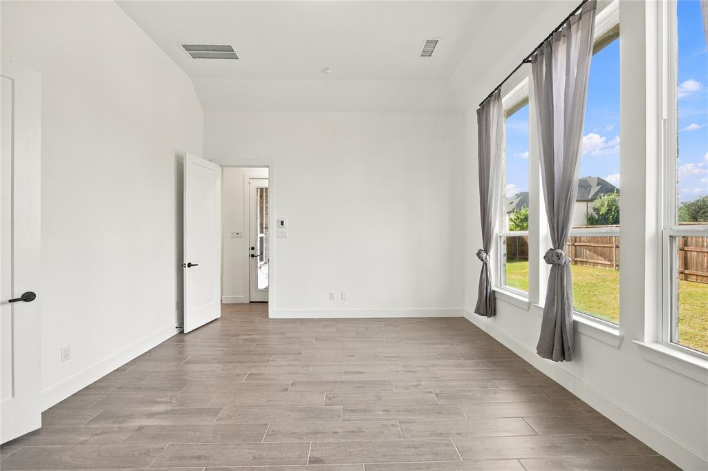 Vaulted ceiling, wood-finish flooring and multiple windows with backyard views