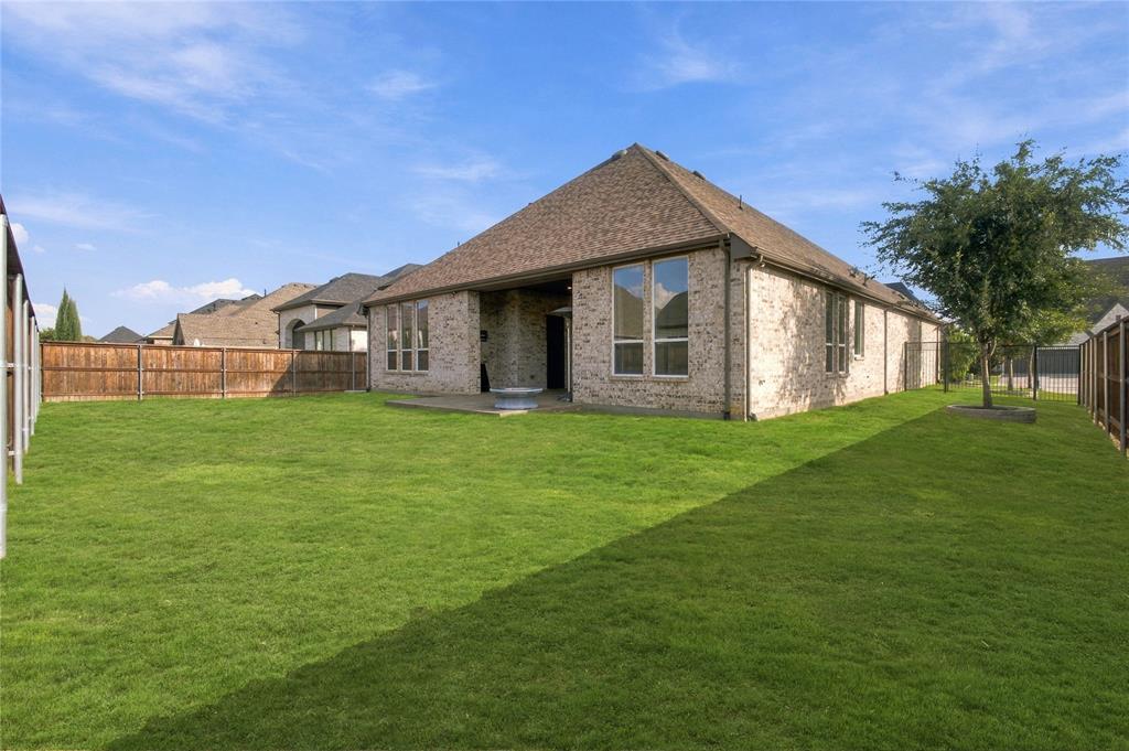 Expansive backyard featuring brick exterior, wood fence, and a mature tree