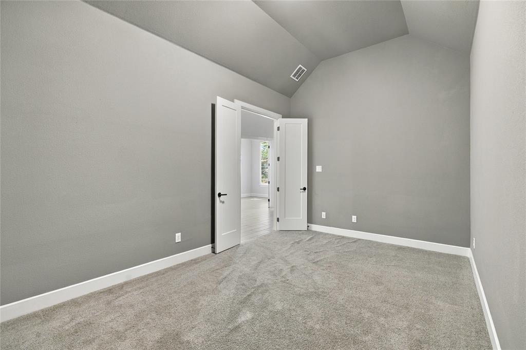 Vaulted ceiling, gray carpeting, neutral wall finishes, and white interior doors with dark hardware