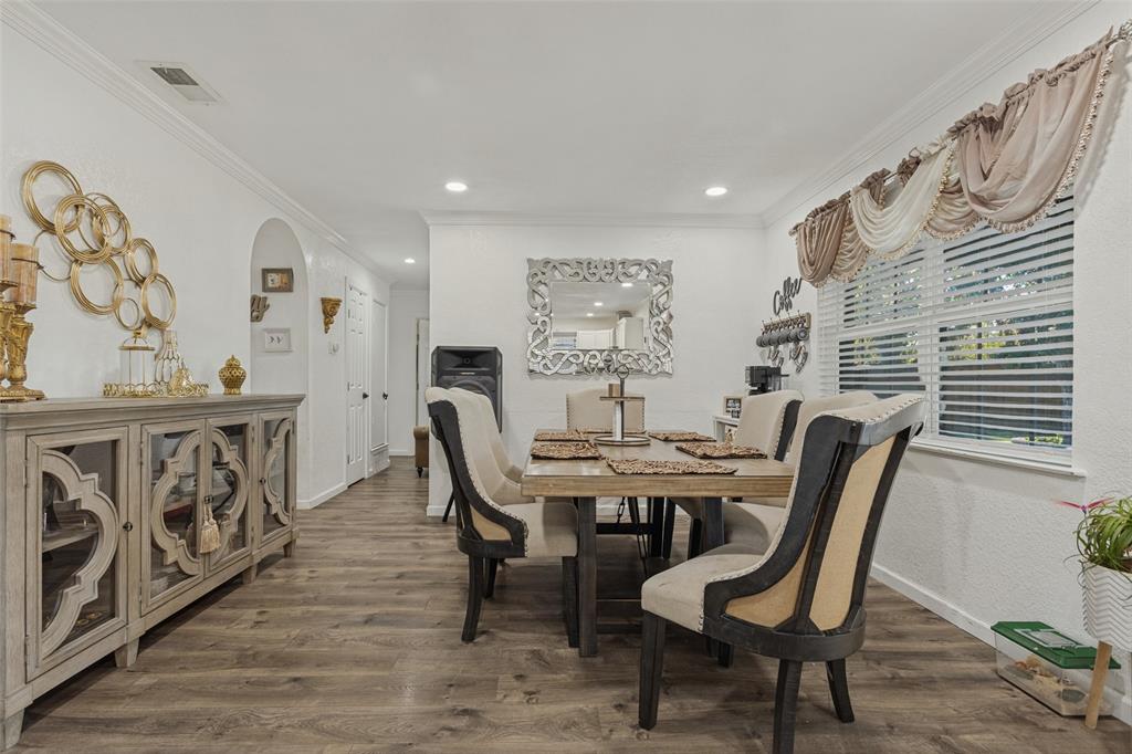 Wood-finish flooring, recessed lighting, crown molding, and an arched entry