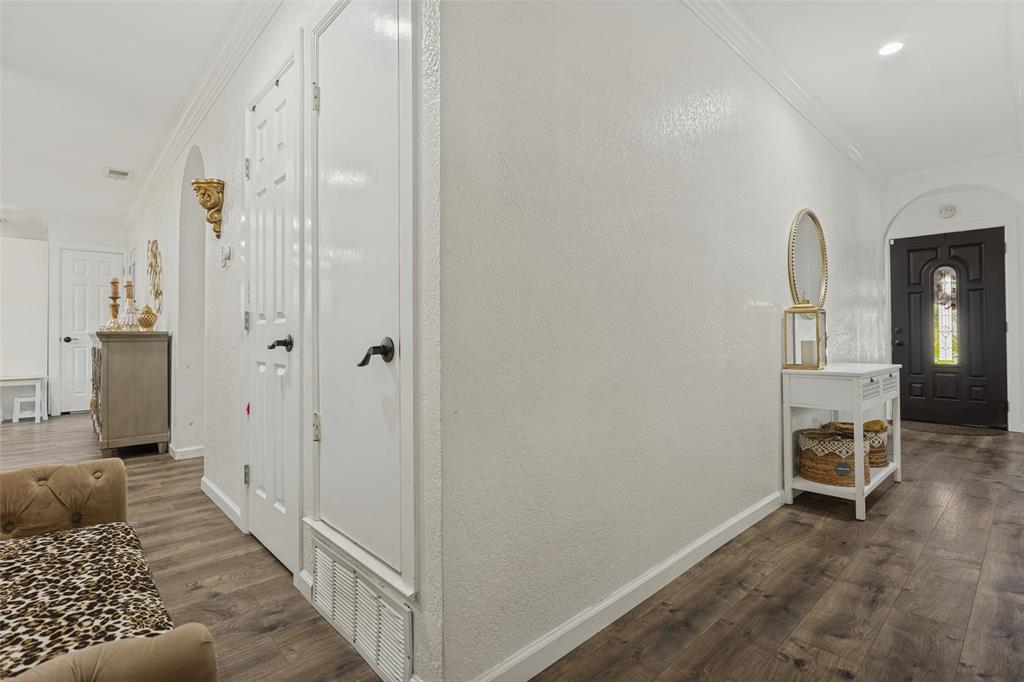 Entryway featuring dark-stained wood-finish flooring, white paneled doors with matte black hardware, arched wall openings, and a dark-finished exterior entry door with an integrated glass panel