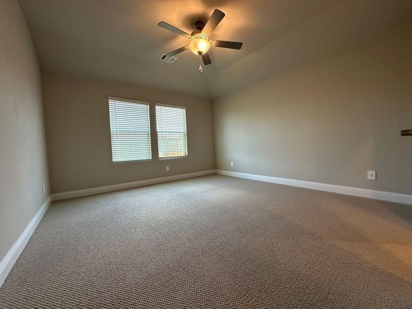 Vaulted ceiling with a ceiling fan, dual windows with blinds, neutral carpeting, and light-toned wall paint