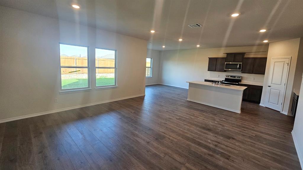 Spacious living area featuring wood-finish flooring, recessed lighting, and multiple windows