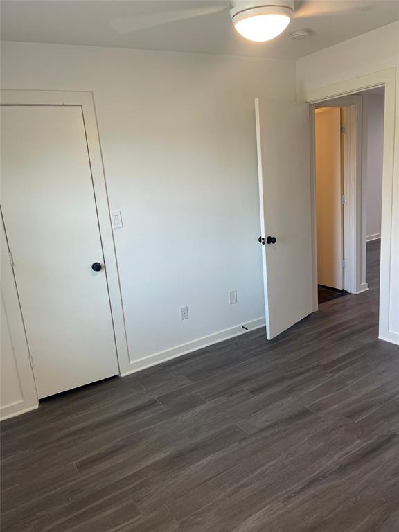 Wood-finish flooring with white walls and trim, featuring a ceiling fan with integrated lighting
