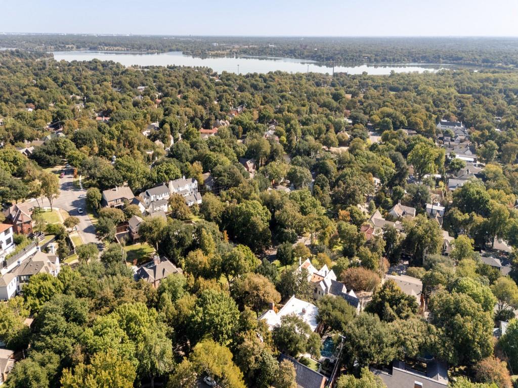 Aerial perspective featuring mature tree canopy, dense residential landscaping, and proximity to a large body of water