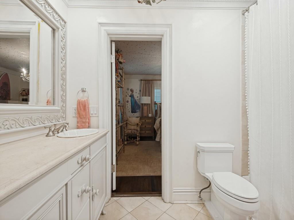 Vanity with a neutral-toned countertop and an integrated oval sink, ornate framed wall mirror, and tile flooring