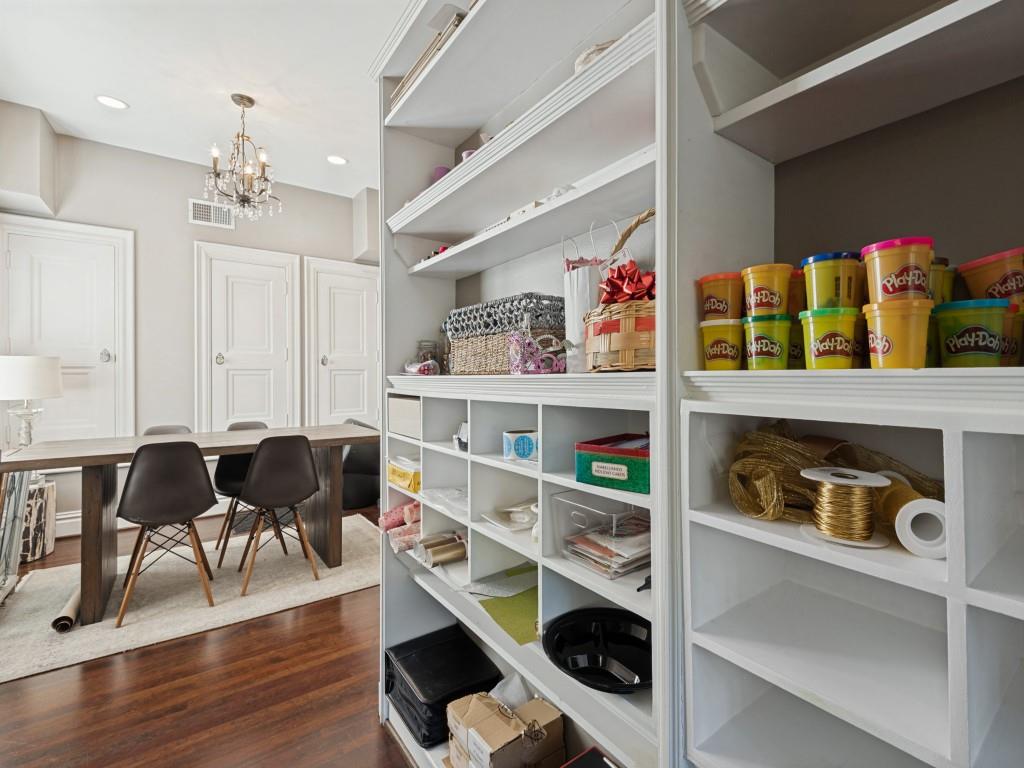 Custom floor-to-ceiling built-in cabinetry featuring extensive shelving and storage cubbies, paired with rich wood flooring, recessed lighting, and a traditional chandelier
