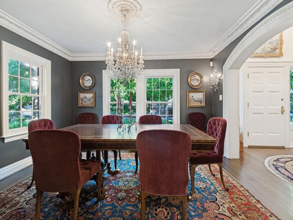 Formal dining room featuring intricate crown molding, a decorative ceiling medallion, a multi-tiered crystal chandelier, wood-finish flooring, and a wide arched entryway