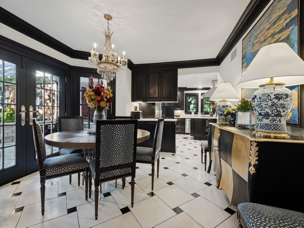 Dining area featuring crown molding, black-framed French doors, a crystal chandelier, and geometric tile flooring