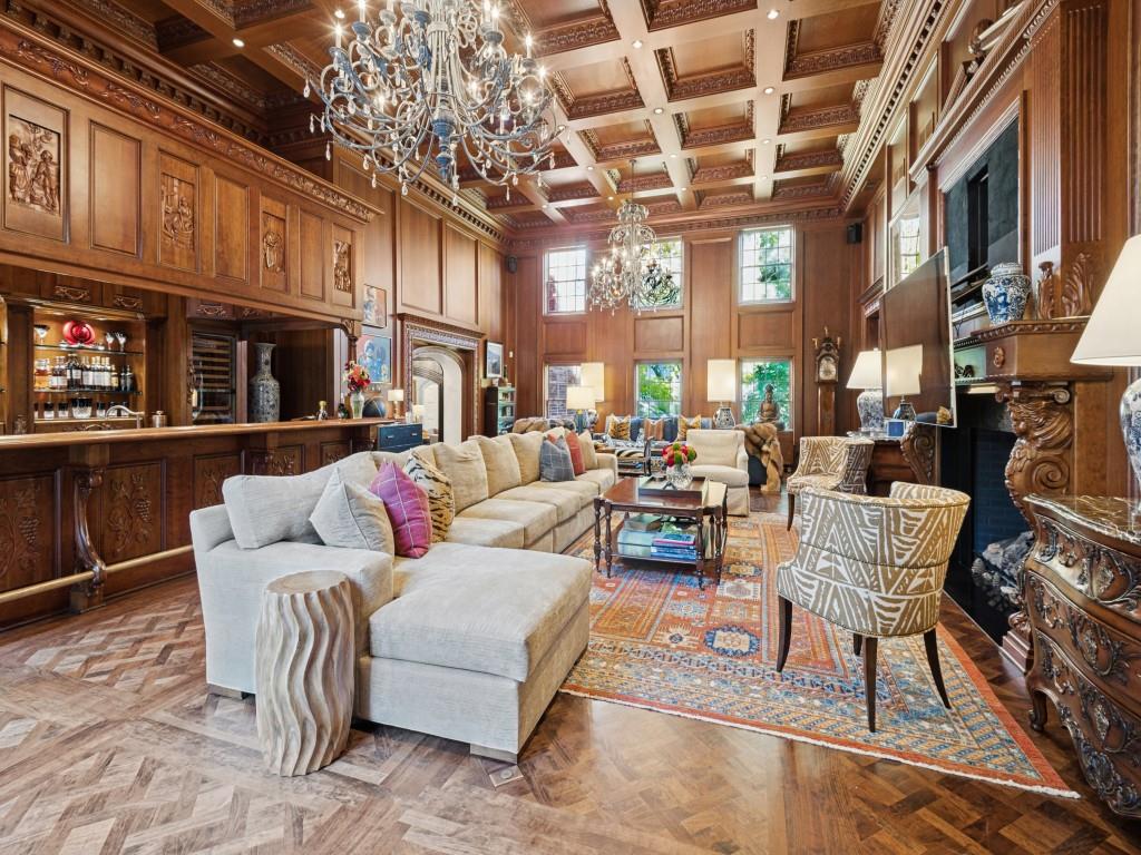 Coffered wood ceiling, intricate wood-paneled walls, built-in wet bar, herringbone-patterned wood flooring, and an ornate fireplace surround Coffered wood ceiling, intricate wood-paneled walls, built-in wet bar, herringbone-patterned wood flooring, and an ornate fireplace surround