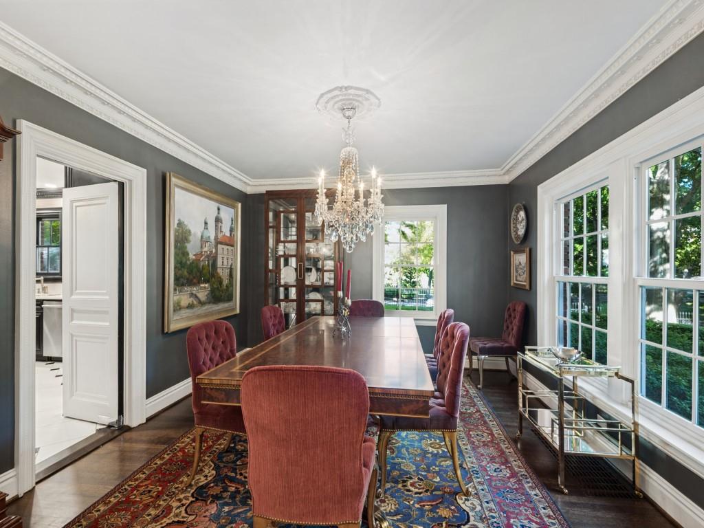 Formal room featuring crown molding, custom ceiling medallion, crystal chandelier, built-in glass-front cabinetry, and wood-finish flooring