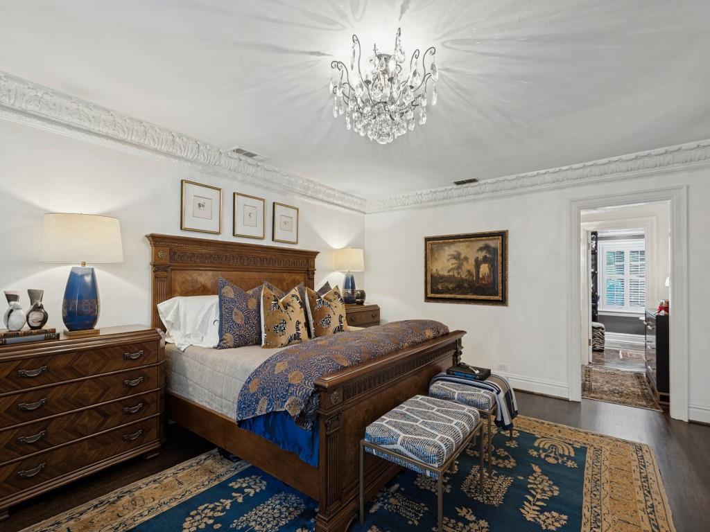 Ornate crown molding, dark wood-finish flooring, and a crystal chandelier