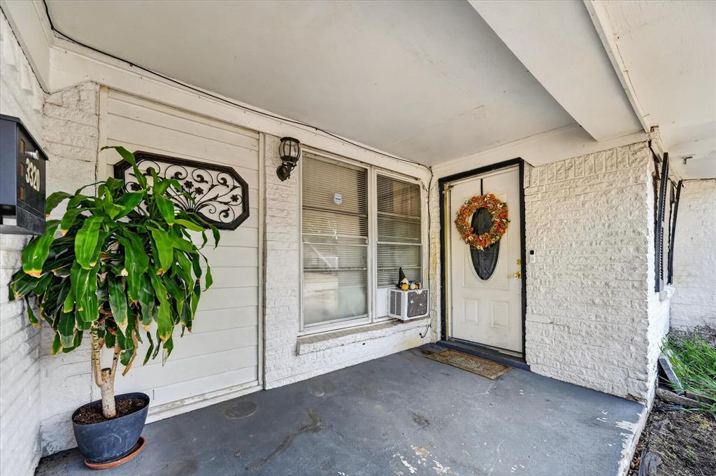 Covered front porch with white painted brick siding and a white entry door