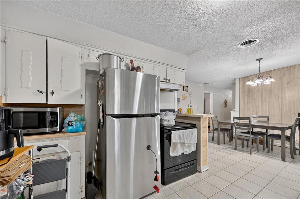 Kitchen featuring white cabinetry, stainless steel appliances, and tile flooring