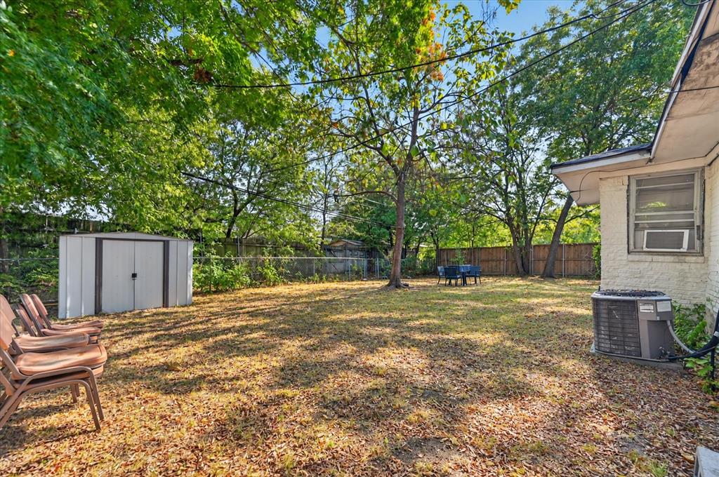 Expansive backyard featuring a mature tree, privacy fencing, and a metal storage shed