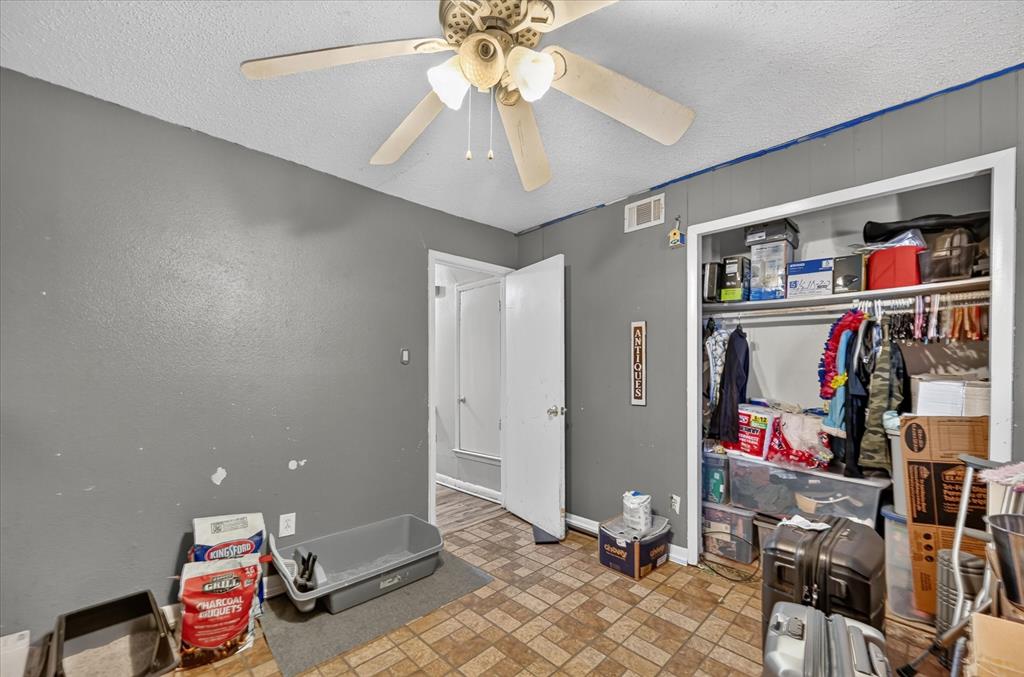 Built-in ceiling fan, textured ceiling, panel accent wall, and a built-in closet with shelving and hanging rod