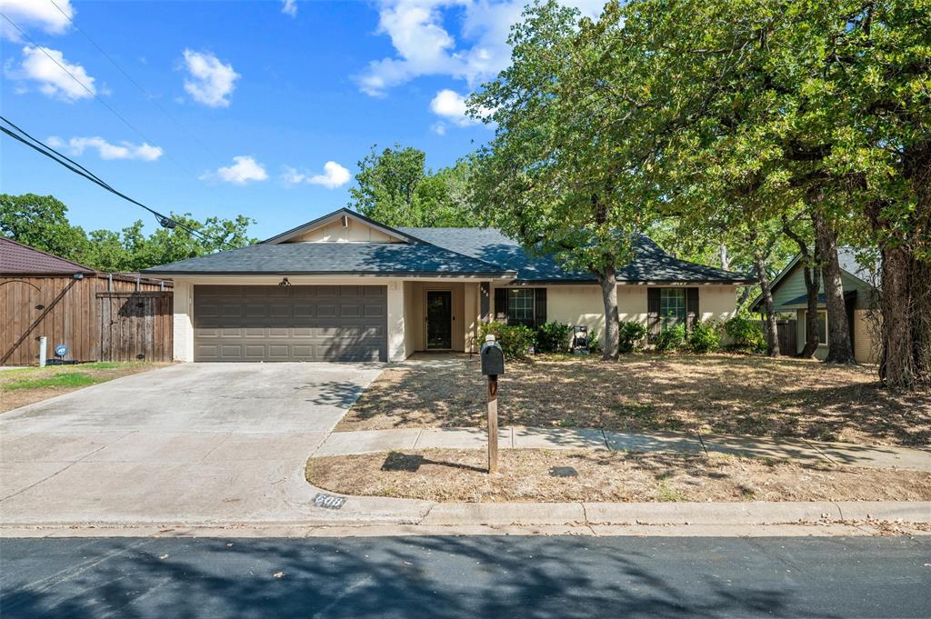 Single-story residence featuring a two-car garage, front yard landscaping, and mature trees