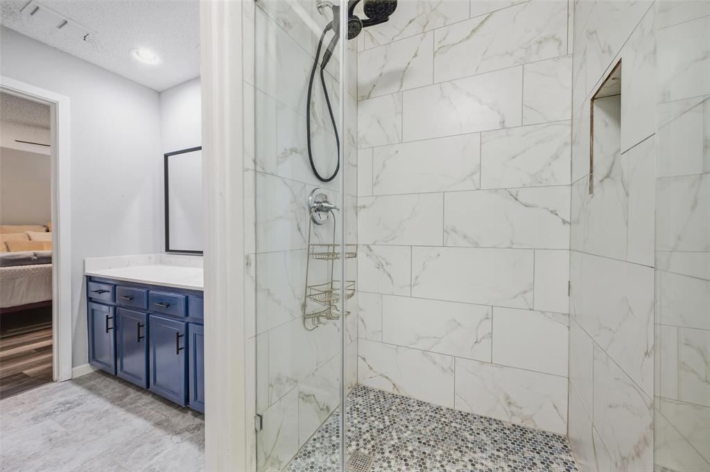 Walk-in shower with clear glass enclosure and mosaic tile floor
