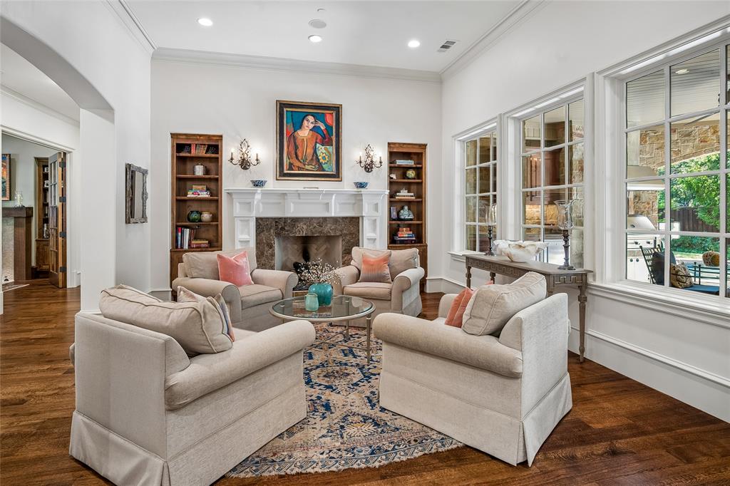 Hardwood flooring, white crown molding, built-in shelving, fireplace with stone surround and white mantel, large grid-pattern windows