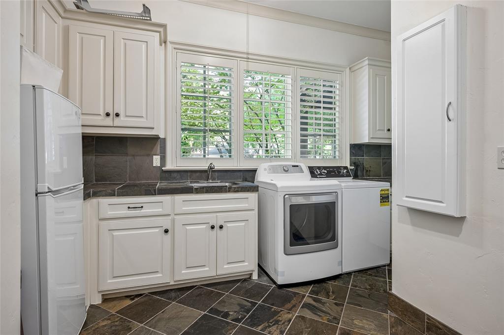 White cabinetry, dark stone tile flooring, dark backsplash, and plantation shutters