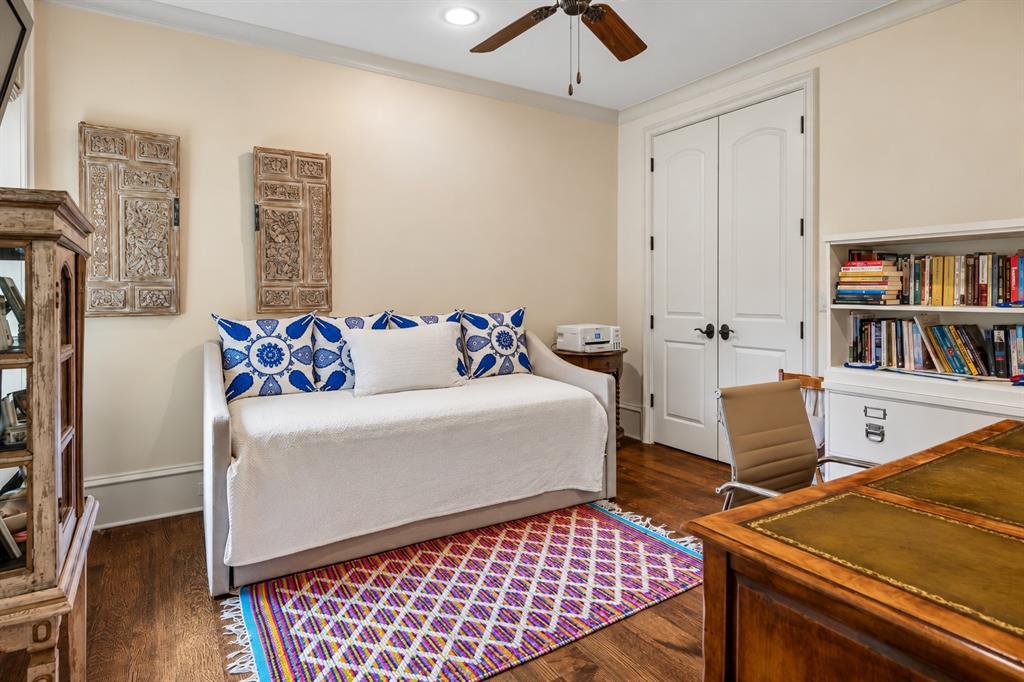 First floor guest bedroom suite. Wood-finish flooring, built-in shelving, white paneled doors, and a ceiling fan