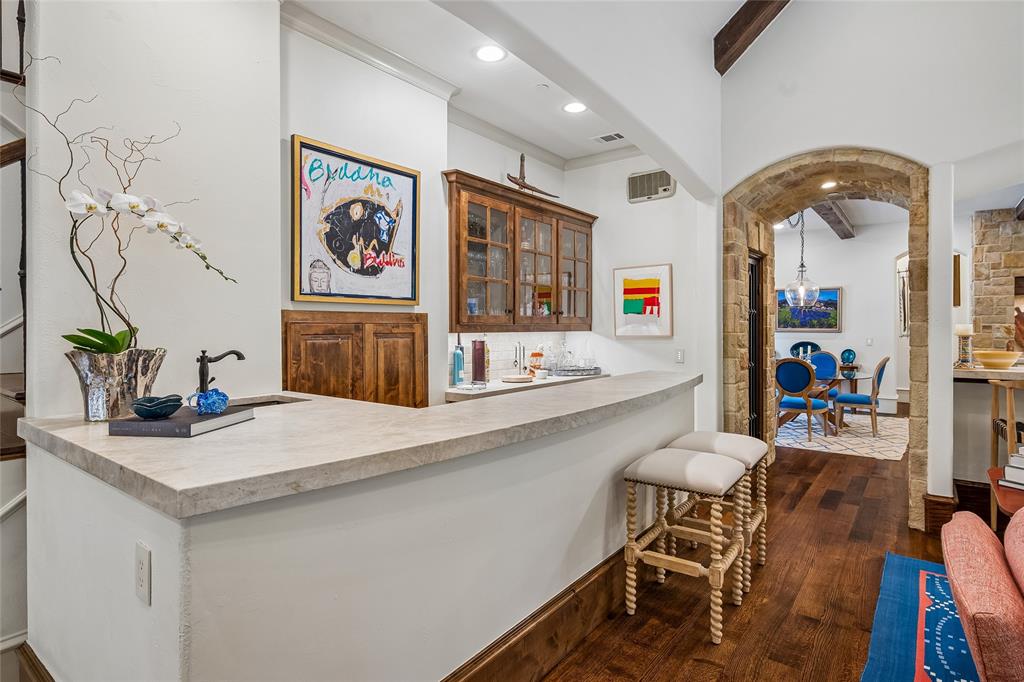 Wet bar with stone-finish countertop, wood-finish cabinetry, and a dark-finish faucet