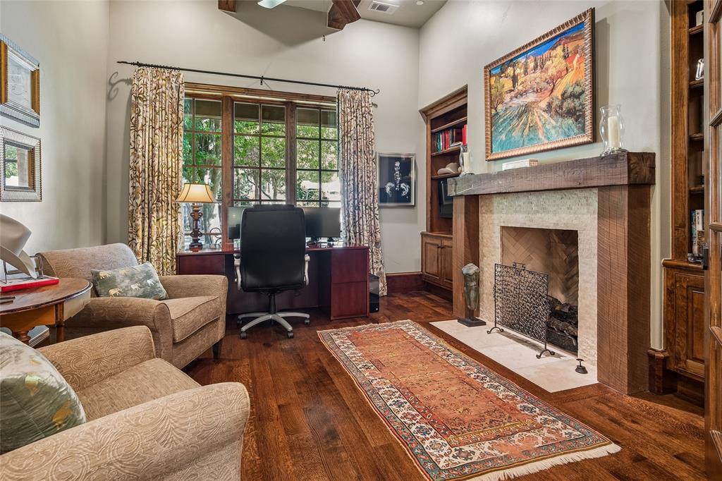 Handsome office or library -Hardwood flooring, fireplace with stone surround and wood mantel, built-in shelving, vaulted ceiling, and wood-frame window