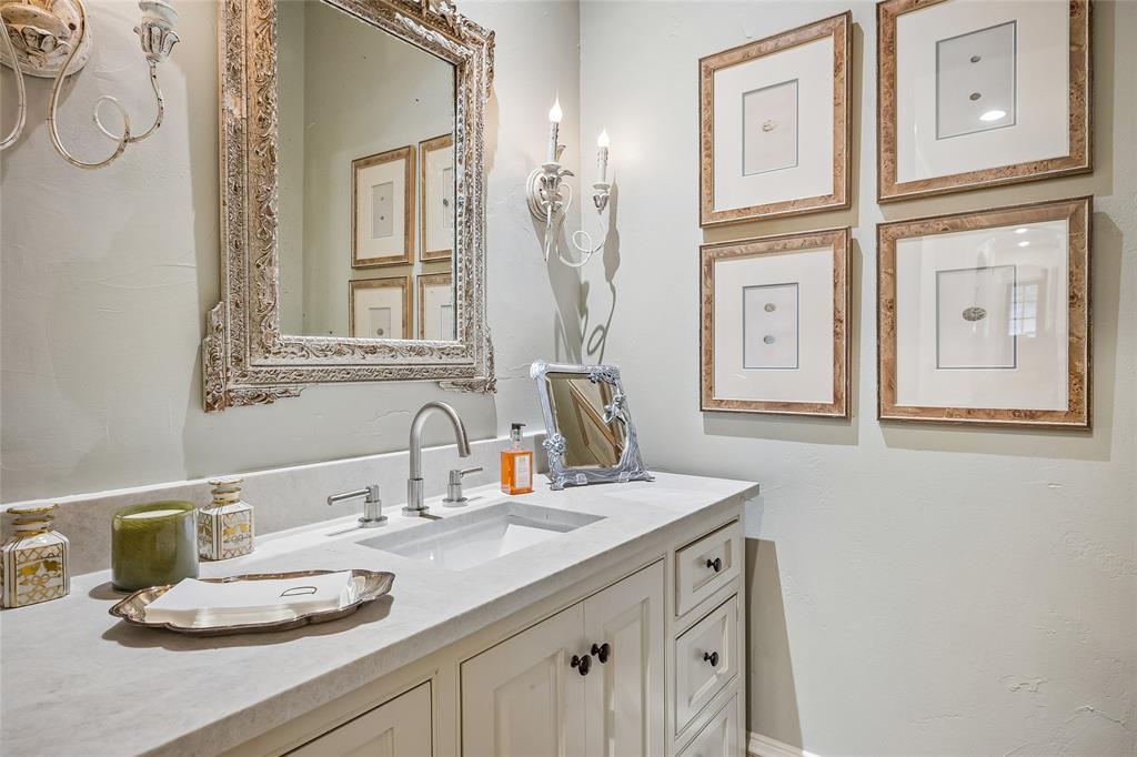 Just one of 8 bathrooms, this powder room offers white vanity with recessed panel cabinet doors and drawers, undermount rectangular sink, light-toned countertop, and a decorative mirror