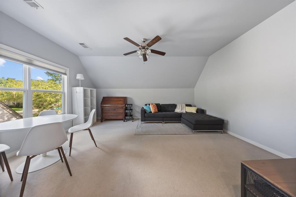 Sloped ceilings, neutral carpet, large windows, ceiling fan, and built-in shelving