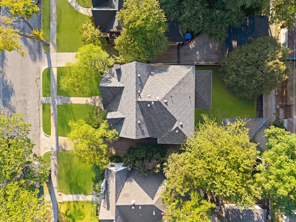 Gabled roofline with multiple pitches, mature perimeter trees, and a manicured lawn