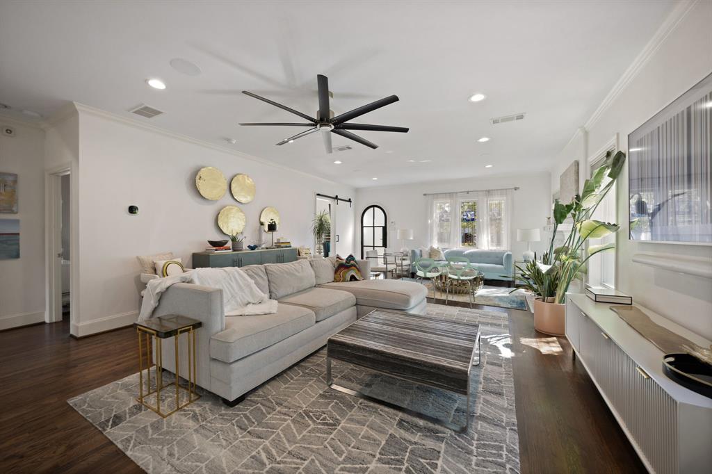 Spacious living area featuring dark wood-finish flooring, recessed lighting, a modern ceiling fan, crown molding, and an arched interior doorway