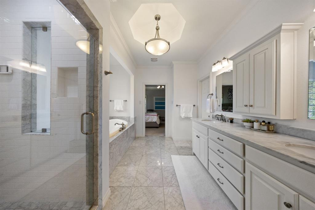 Elongated bathroom featuring a glass-enclosed shower, built-in soaking tub, dual vanity with undermount sinks, and integrated cabinetry
