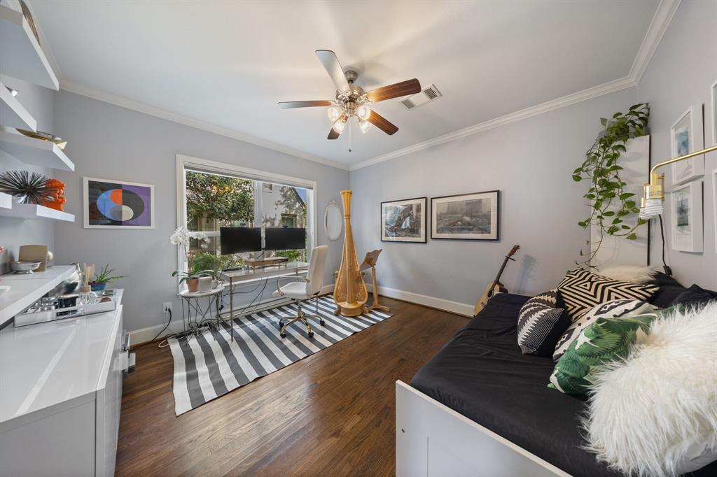 Hardwood-finish flooring throughout, crown molding, a ceiling fan with integrated lighting, and a large window
