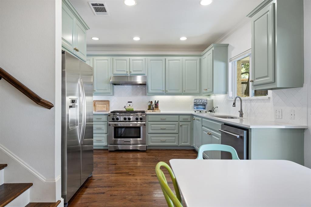 Kitchen featuring light green cabinetry, stainless steel appliances, white countertops, a tiled backsplash, and recessed lighting