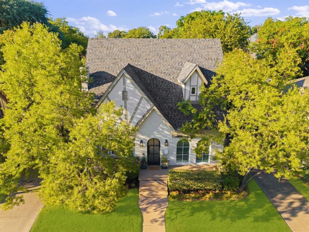 Gabled roofline, dormer window, Tudor-style facade, arched entry, mature landscaping