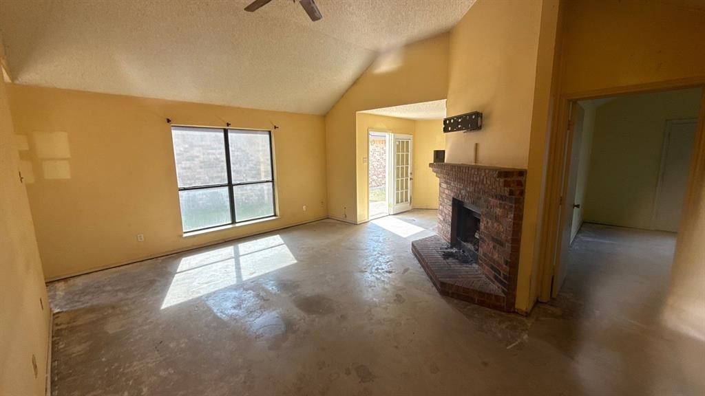 Vaulted ceilings, brick fireplace, French doors, ceiling fan, and large windows