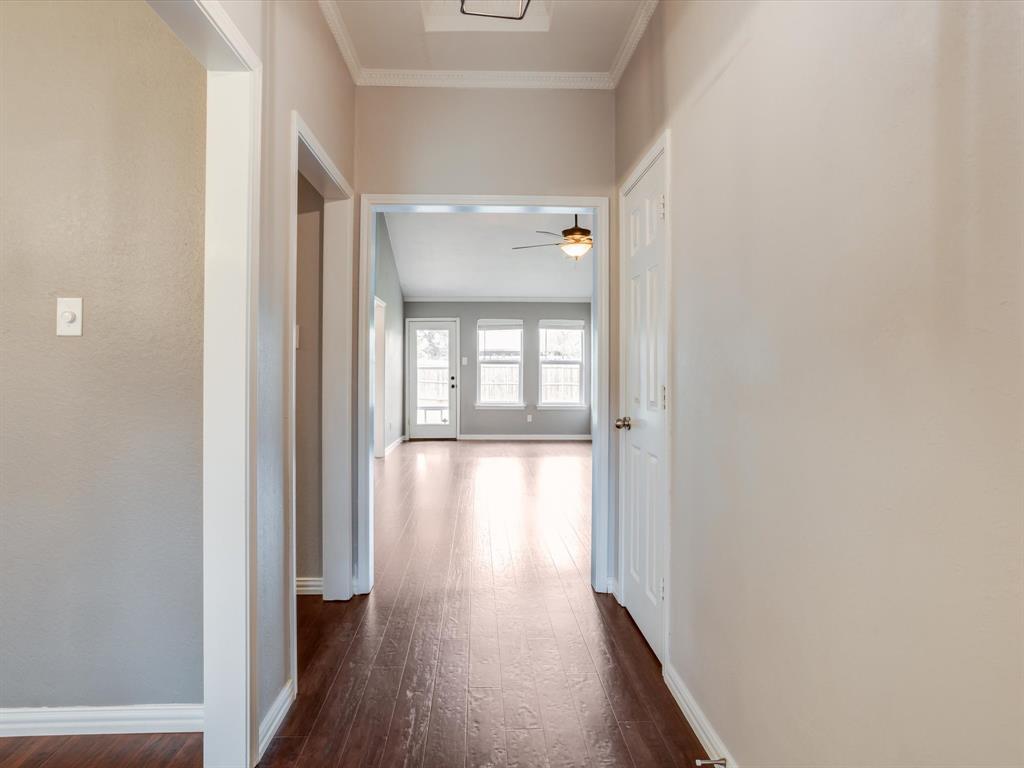 Interior hallway featuring wood-finish flooring, neutral wall paint, crown molding, and six-panel interior doors