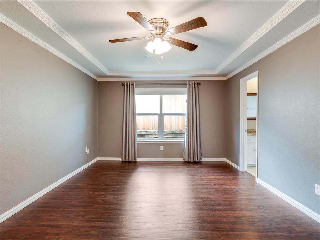 Tray ceiling with crown molding, wood-finish flooring, and a central ceiling fan with integrated lighting