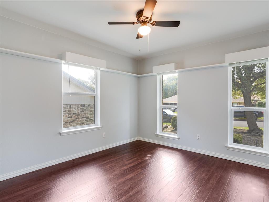 Interior space featuring dark wood-finish flooring, three windows with custom valances, and a ceiling-mounted light fixture with integrated fan