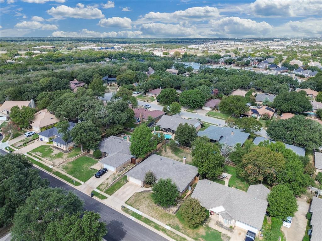 Aerial perspective of a residential neighborhood featuring mature trees, paved streets, and a variety of single-story architectural styles