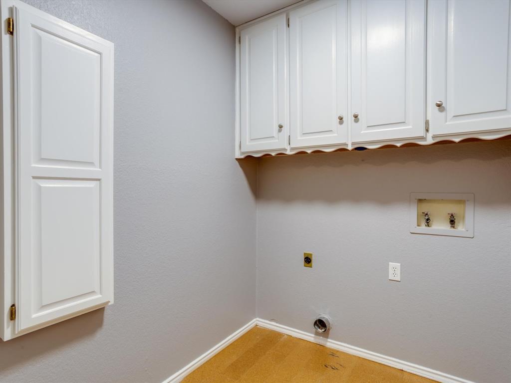 Utility area featuring white shaker-style wall-mounted cabinetry, integrated water hookups, and wood-finish flooring