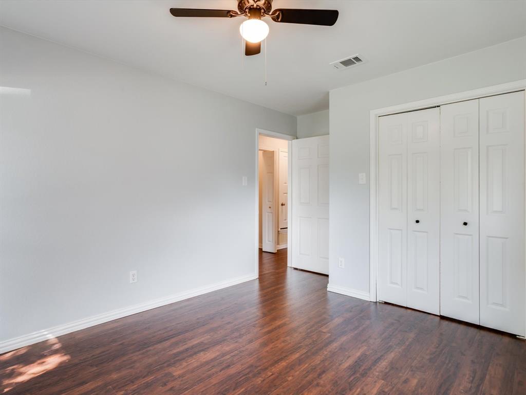 Wood-finish flooring, neutral wall tones, multi-panel closet doors, and a ceiling-mounted light fixture with fan