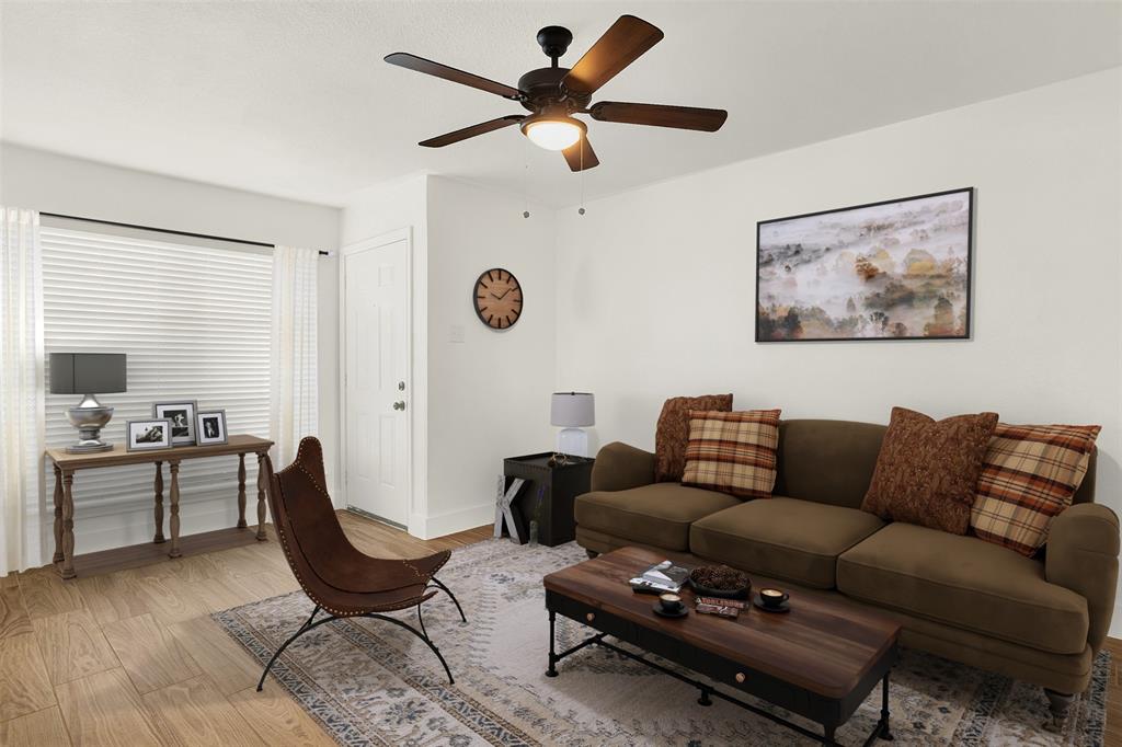 Living room with light wood-type flooring and ceiling fan (Virtual Staged)